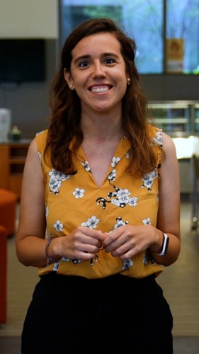 head and shoulders head on portrait of a long haired smiling person in a sleeveless yellow top