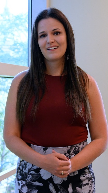 head and shoulders portrait of long dark haired person in red sleeveless shirt